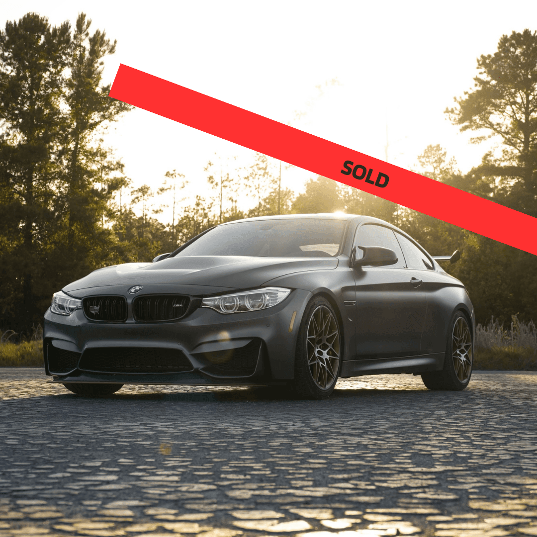 Black sport sedan parked with a red 'SOLD' banner overlay.