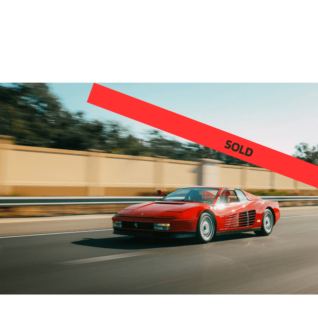 Red sports car driving on a road with 'SOLD' banner across the image.